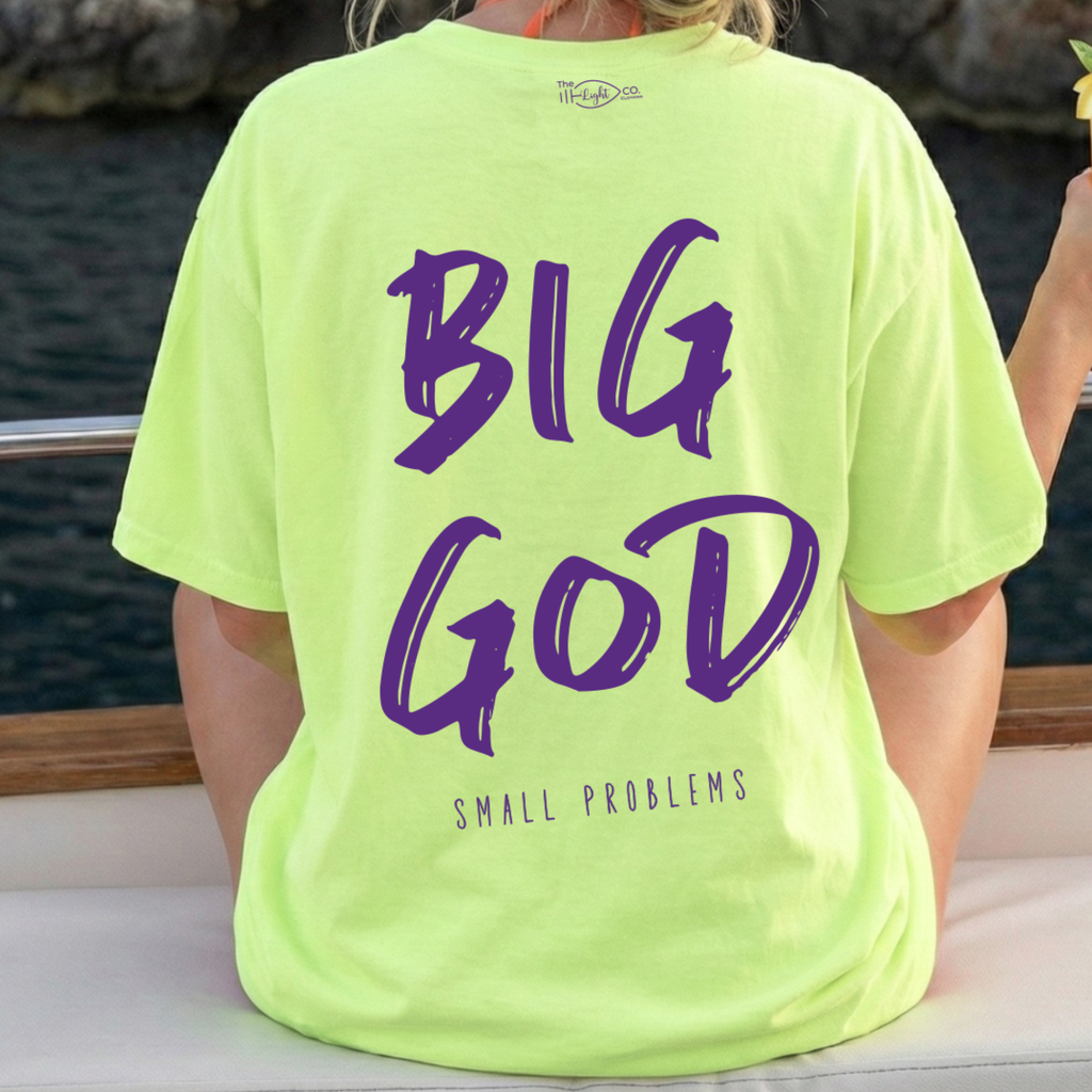 Person wearing a bright green t-shirt with purple text by a body of water.